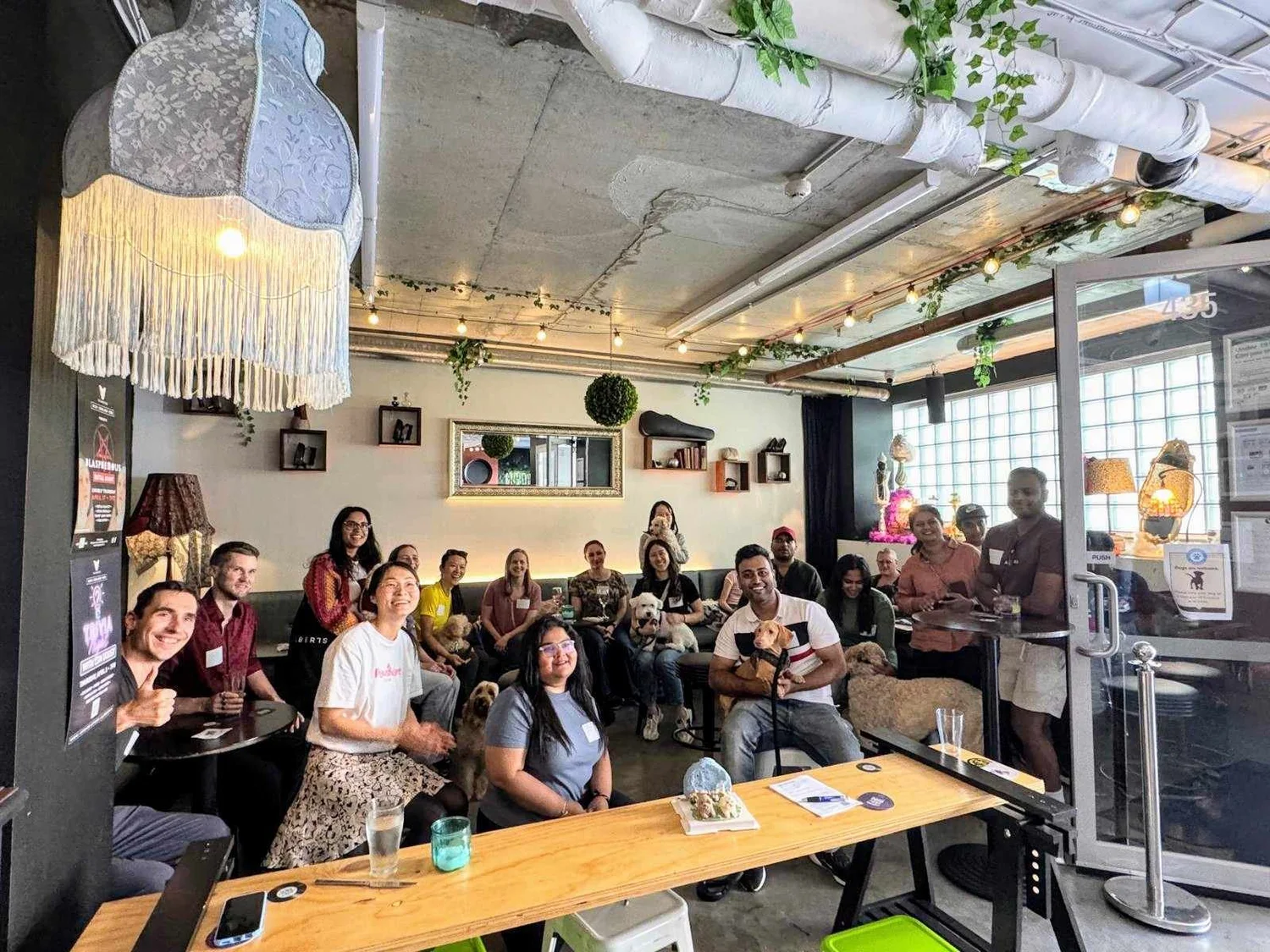 Pawshare Club members gathered with their dogs around a long table inside a cafe