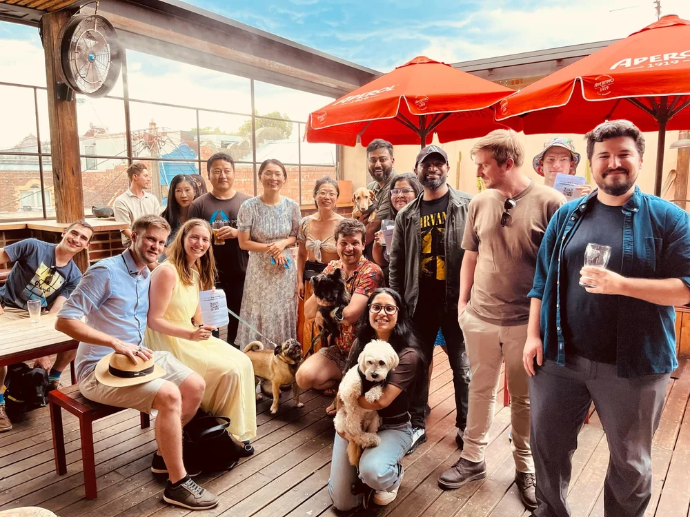Pawshare Club members and their dogs gathered on a cafe terrace beneath red umbrellas