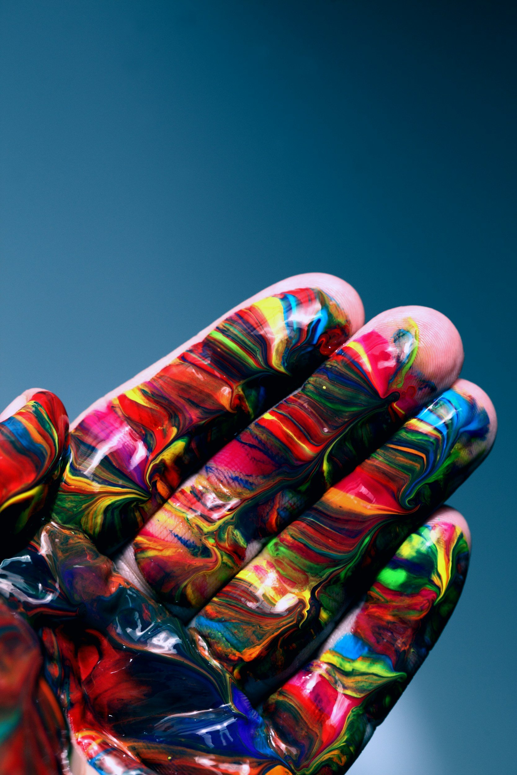 Two hands covered in bright paint held together